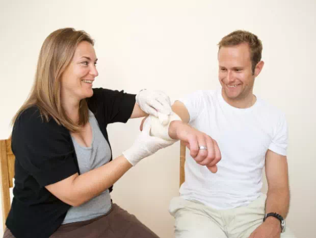 Kobieta bandażuje rękę mężczyźnie